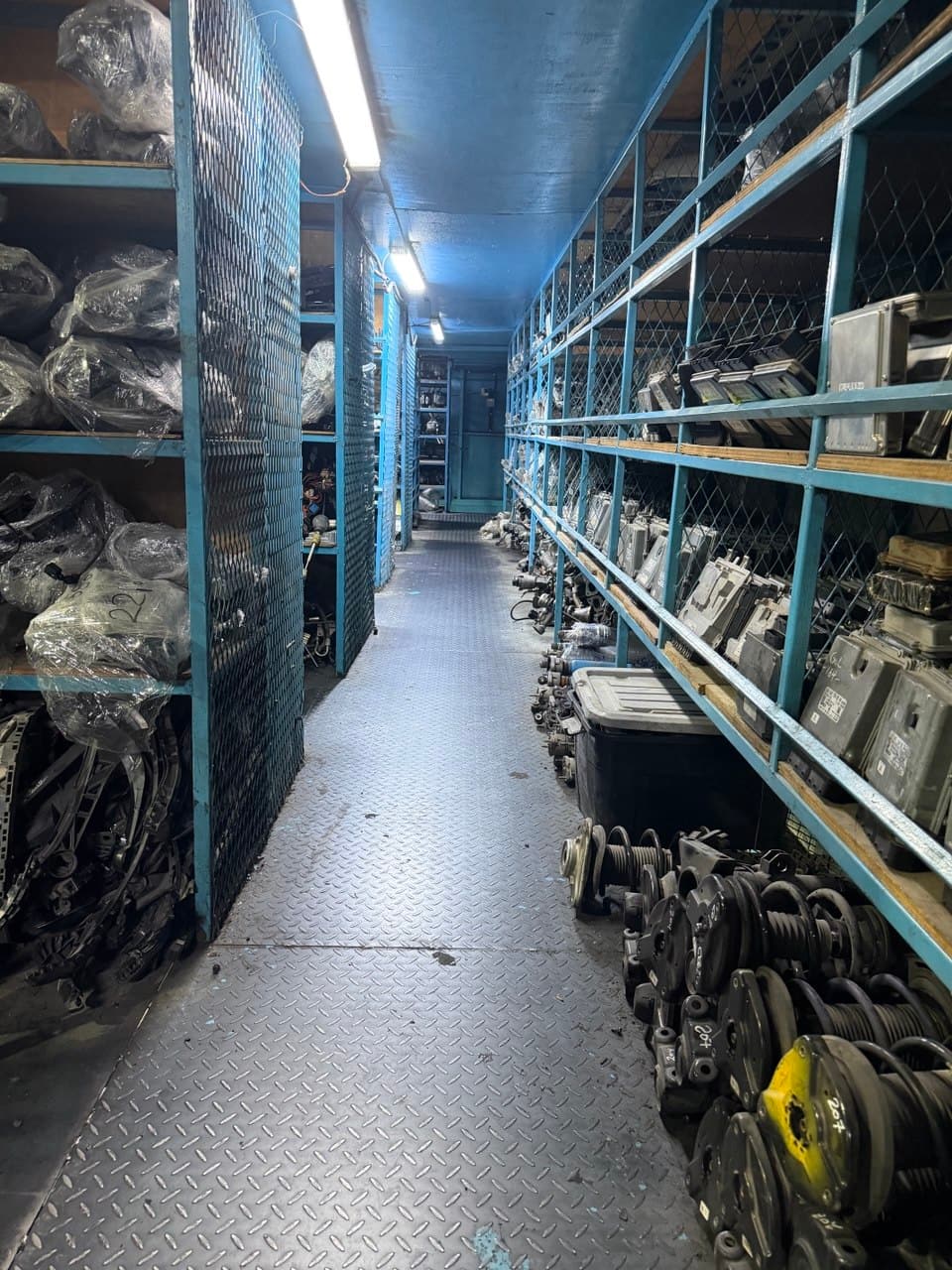 ممر طويل من الرفوف المعدنية تحمل قطعاً مغلفة ومعبأة